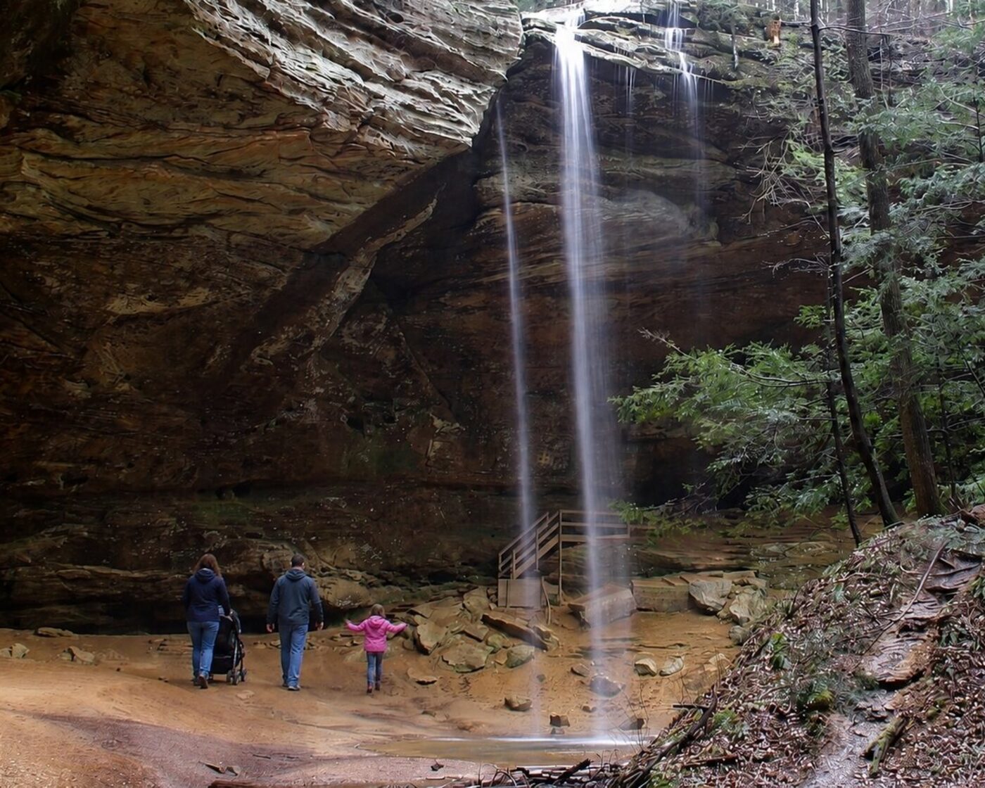 A family with a stroller on the paved trail under Ash Cave