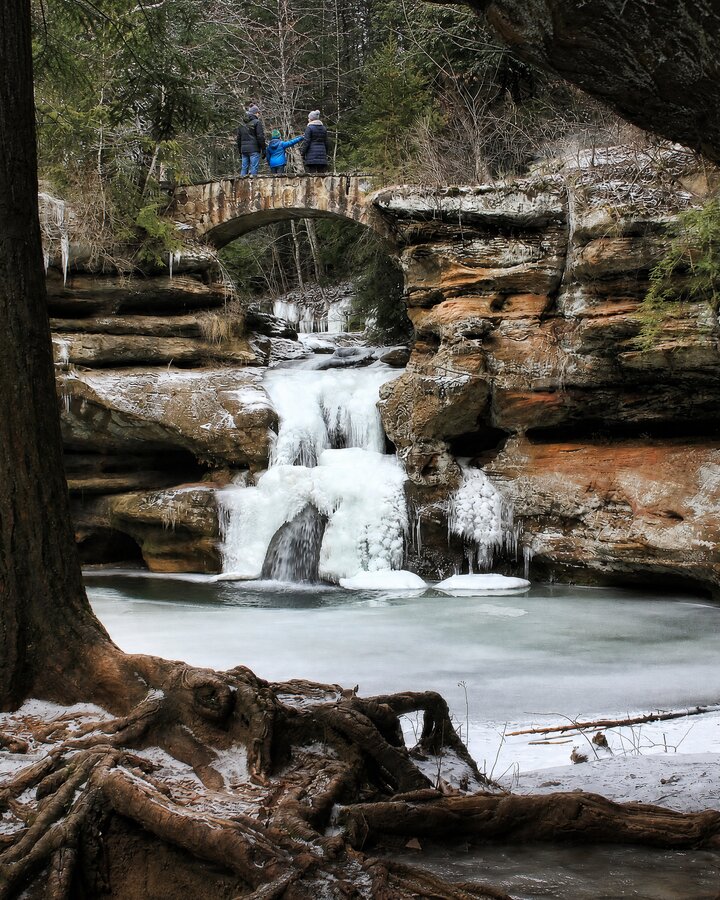 A family on the stone bridge above the frozen Upper Falls